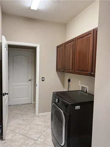 Laundry room featuring washer / dryer, a textured ceiling, and cabinet space