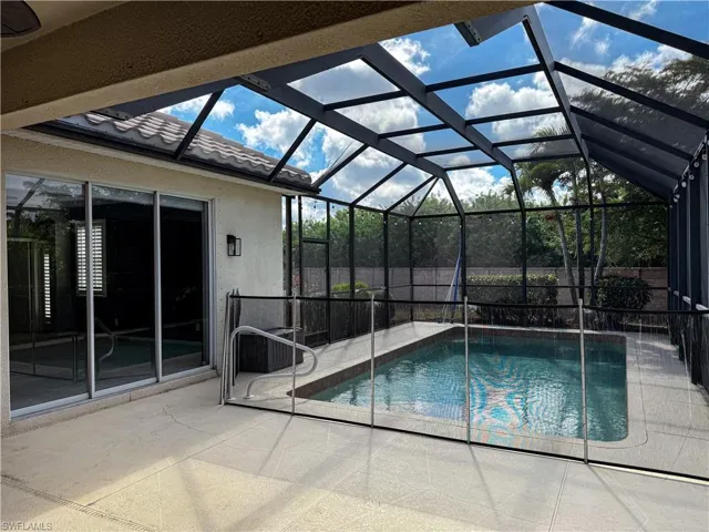 View of swimming pool with patio surround, a sunroom, and glass enclosure