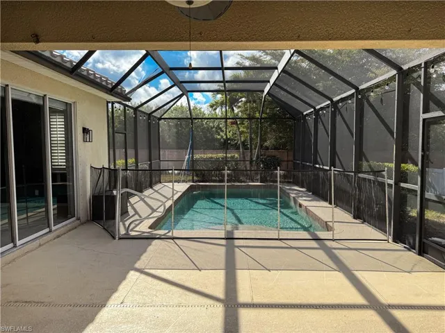 View of swimming pool featuring patio surround, glass enclosure, and a sunroom