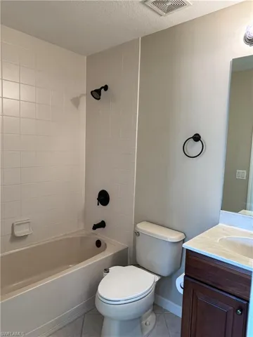 Full bathroom featuring vanity, light tile patterned flooring, a textured ceiling, and  shower combination