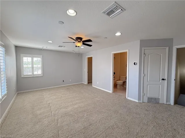 Unfurnished bedroom with light colored carpet, recessed lighting, a ceiling fan, connected bathroom, and a textured ceiling