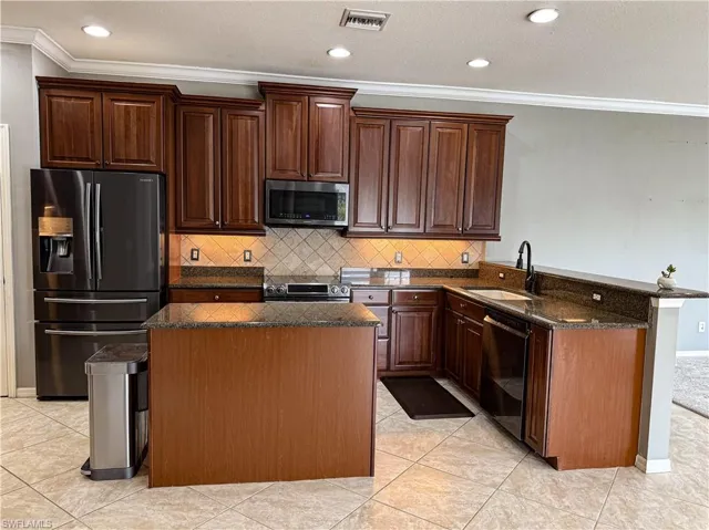 Kitchen with black appliances, a peninsula, crown molding, tasteful backsplash, and a textured ceiling
