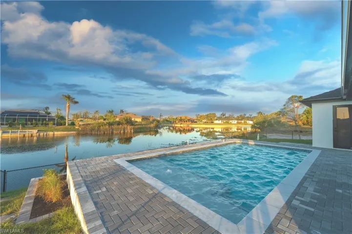 View of swimming pool with a water view and a patio area