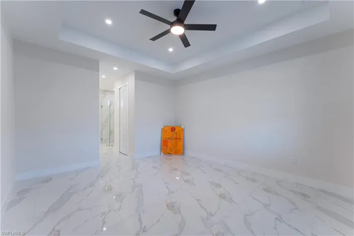 Spare room featuring a tray ceiling and ceiling fan