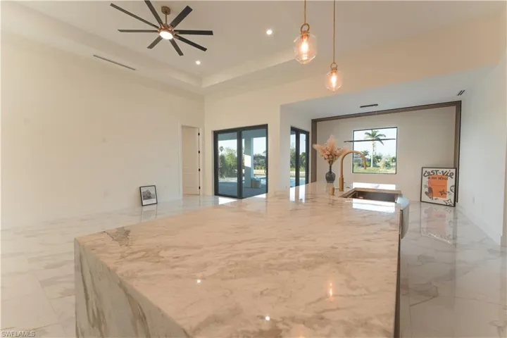 Kitchen featuring pendant lighting, plenty of natural light, and a center island with sink