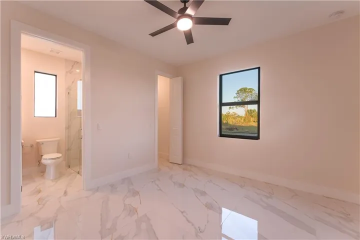 Unfurnished bedroom with ensuite bathroom and ceiling fan