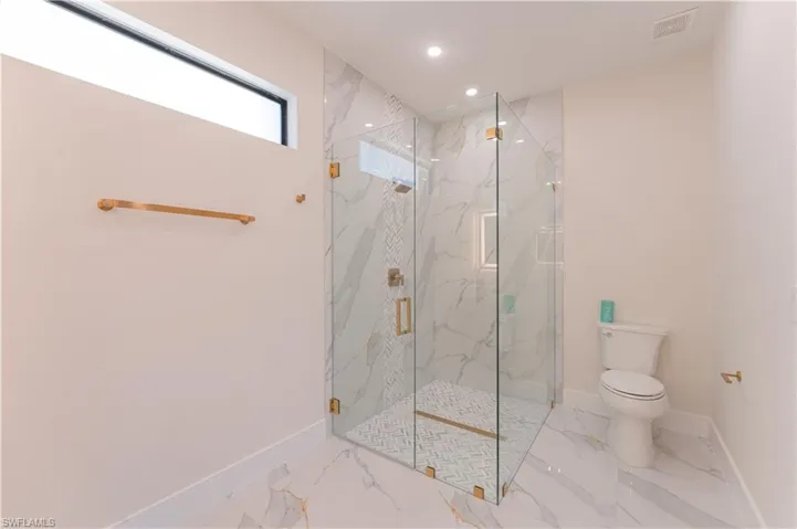 Bathroom featuring toilet and a shower with shower door