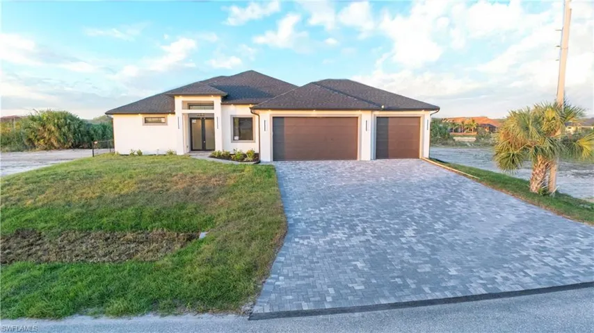 View of front facade featuring a garage and a front lawn