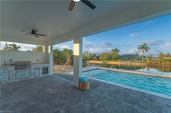 View of pool with sink, exterior kitchen, a water view, grilling area, and a patio