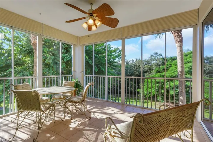 Sunroom / solarium with a ceiling fan, plenty of natural light, and view of wooded area