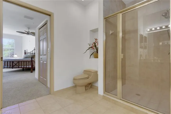 Bathroom featuring light carpet, ensuite bath, a stall shower, and light tile patterned floors