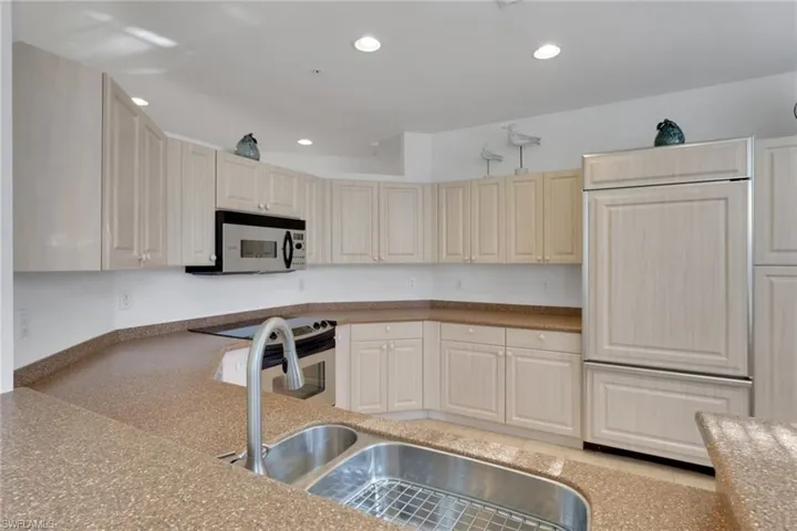 Kitchen featuring appliances with stainless steel finishes, recessed lighting, and light stone counters