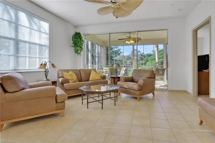 Living area with plenty of natural light, light tile patterned floors, and a ceiling fan