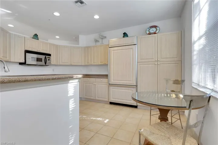 Kitchen with paneled built in refrigerator, light tile patterned flooring, recessed lighting, and stainless steel microwave