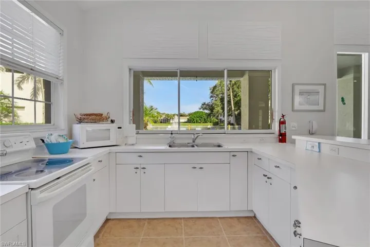 Kitchen featuring white appliances, light countertops, white cabinetry, and light tile patterned floors