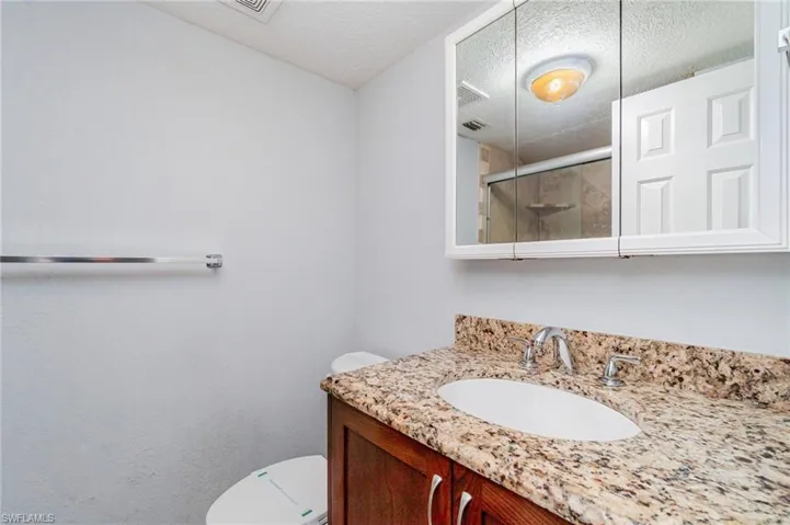 Bathroom with a shower stall, vanity, and a textured ceiling