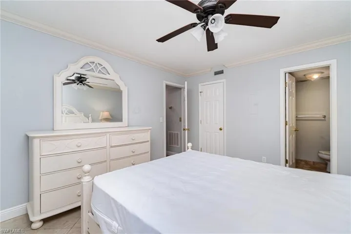 Bedroom featuring ornamental molding, light tile patterned floors, connected bathroom, and ceiling fan