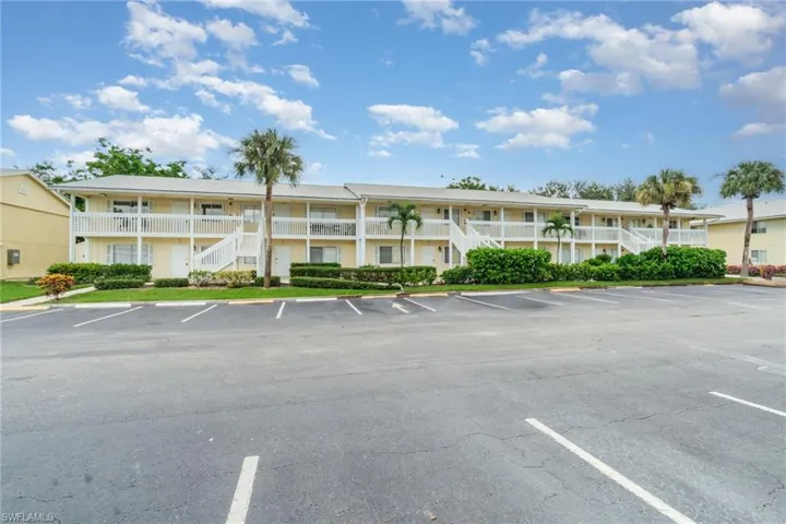 View of property featuring stairway and uncovered parking