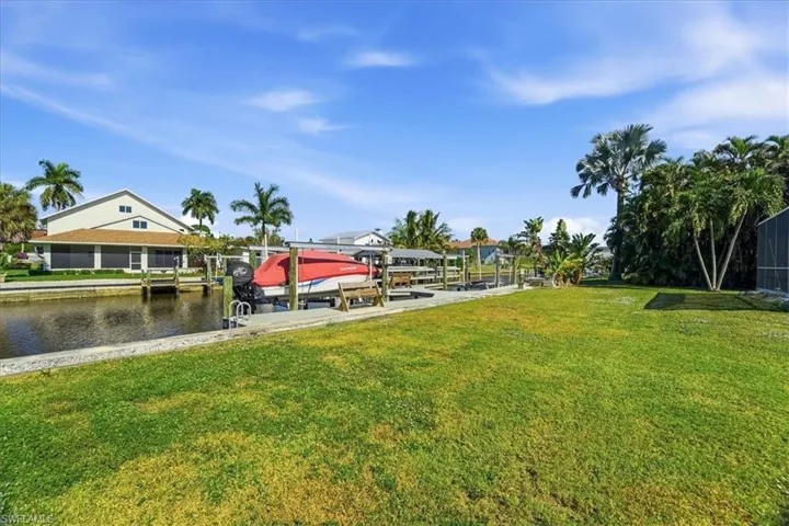 Dock area with boat lift, a yard, and a water view