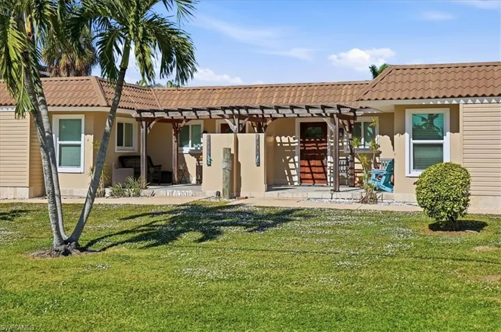 Rear view of house featuring a pergola, a yard, stucco siding, and a patio