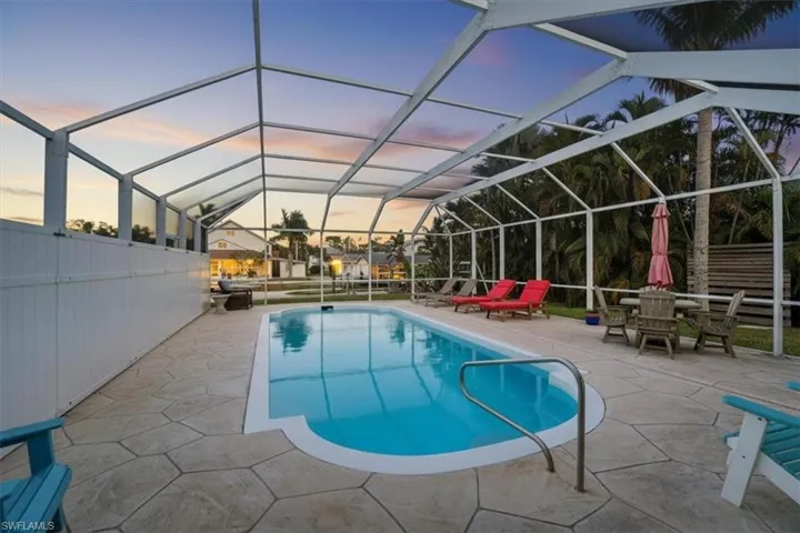 Pool at dusk featuring an outdoor pool, a lanai, a sunroom, and a patio
