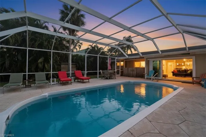 Pool at dusk featuring an outdoor pool, a lanai, and a sunroom