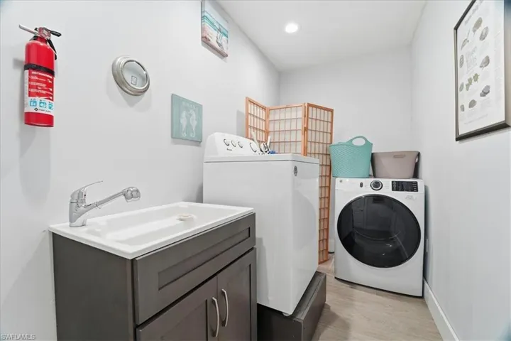 Washroom featuring washer and clothes dryer, light wood-type flooring, and recessed lighting