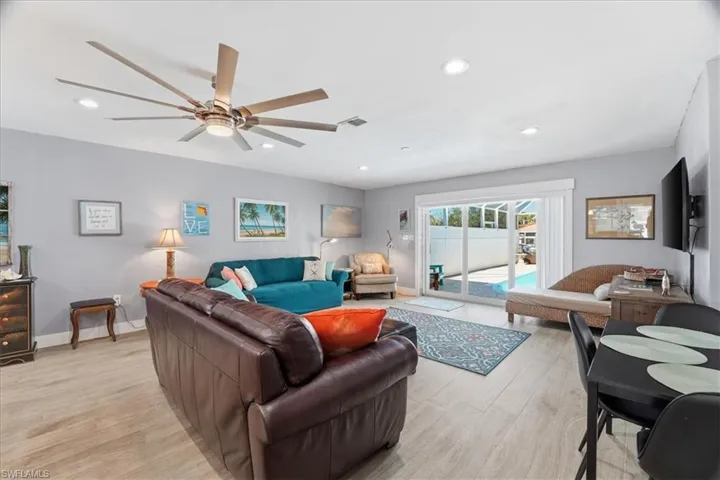 Living room with light wood-style floors, ceiling fan, and recessed lighting