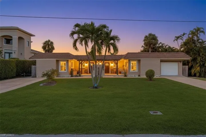 Ranch-style home with a tiled roof, driveway, a front yard, and an attached garage