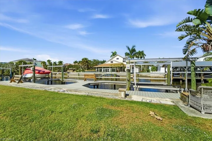 Dock area with boat lift, a lawn, and a water view