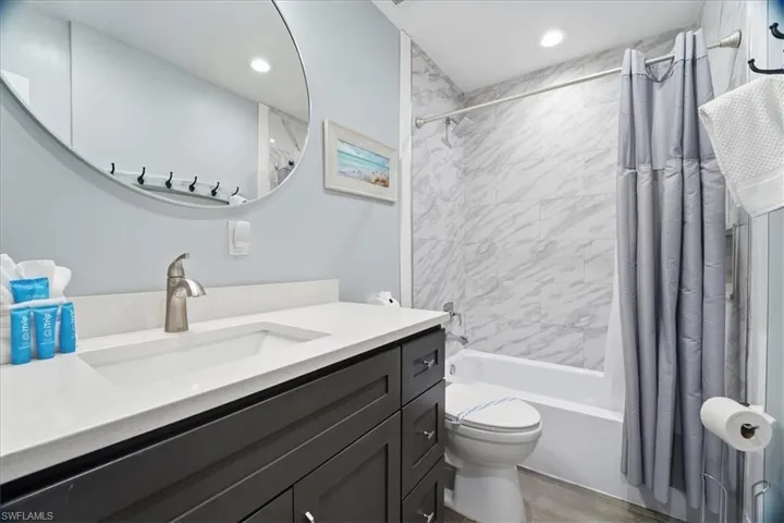 Bathroom with shower / bathtub combination with curtain, vanity, recessed lighting, and light wood-style floors