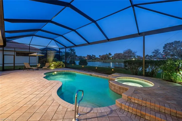 View of pool with a water view, an in ground hot tub, glass enclosure, and a patio