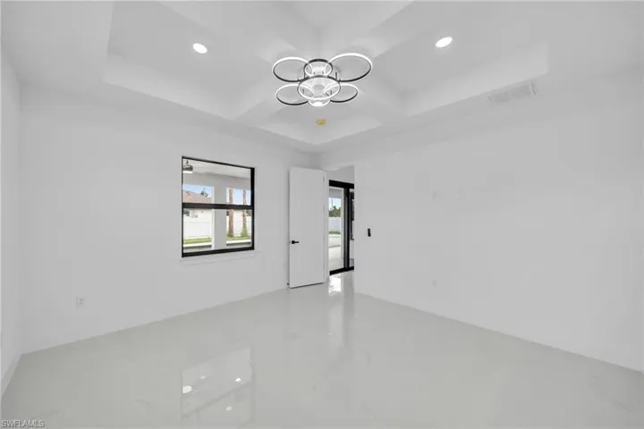 Empty room with a raised ceiling, coffered ceiling, and an inviting chandelier