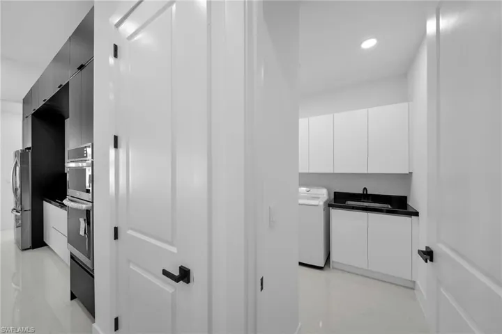 Kitchen with washer / clothes dryer, stainless steel fridge, sink, and white cabinets