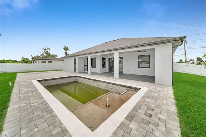 Rear view of property featuring a fenced in pool, a patio area, a lawn, and ceiling fan