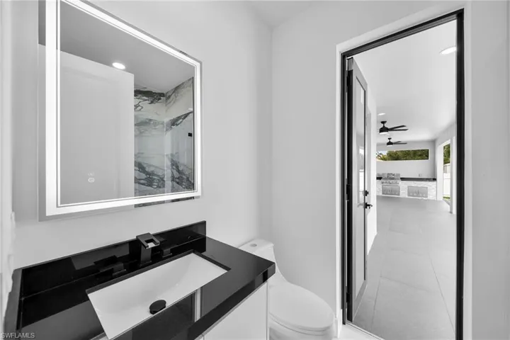 Bathroom with tiled shower, vanity, tile patterned flooring, and toilet