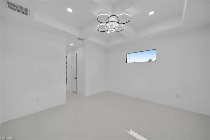Spare room featuring an inviting chandelier, a raised ceiling, and coffered ceiling