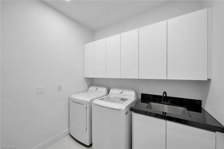 Laundry area featuring sink, cabinets, and washer and clothes dryer