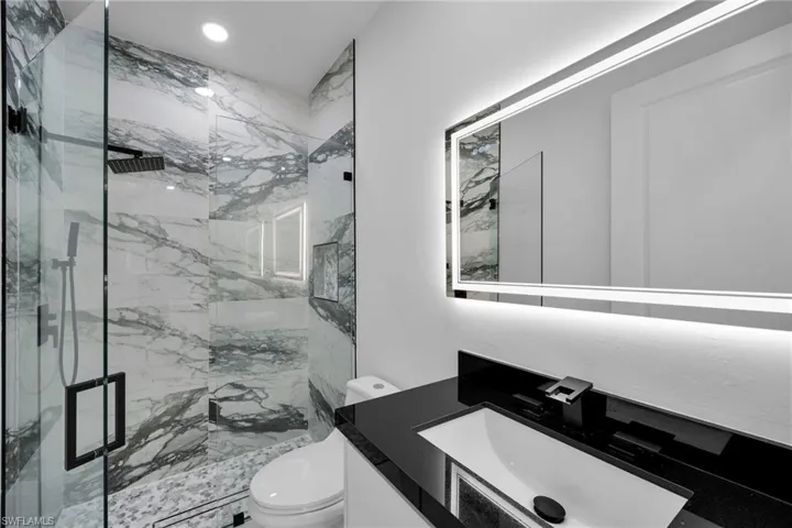 Bathroom featuring vanity, a shower with door, and toilet