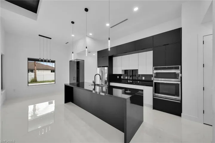 Kitchen featuring decorative backsplash, pendant lighting, an island with sink, sink, and appliances with stainless steel finishes