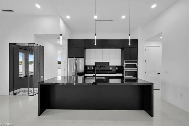Kitchen with appliances with stainless steel finishes, pendant lighting, backsplash, an island with sink, and white cabinetry