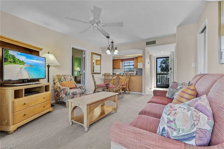 Carpeted living room with ceiling fan with notable chandelier