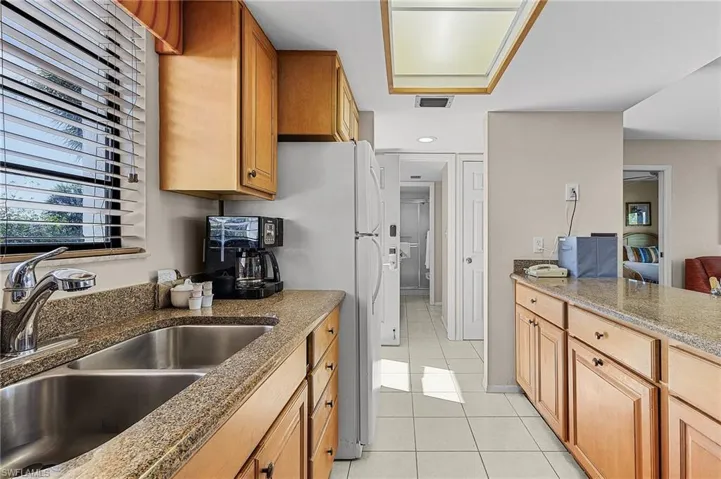 Kitchen with light tile patterned flooring, sink, and stone countertops
