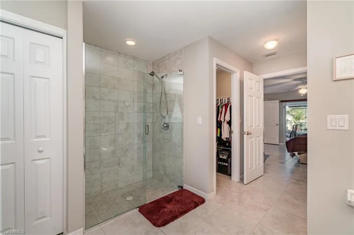Ensuite bathroom featuring a glass enclosed shower and linen closet.