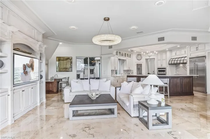 Living area featuring ornamental molding, a chandelier, light marble finish flooring, and recessed lighting