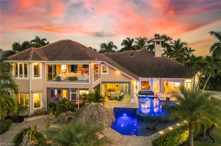 Back of house at dusk featuring an outdoor pool, a chimney, an outdoor living space, a patio, and stucco siding