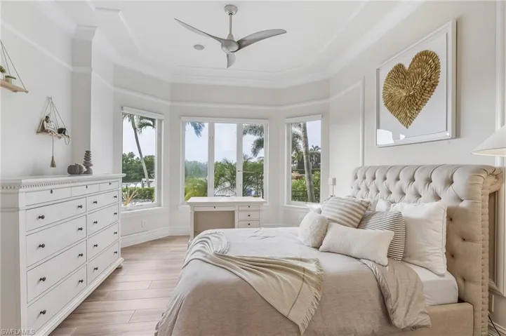 Bedroom featuring a ceiling fan, crown molding, and light wood-style flooring