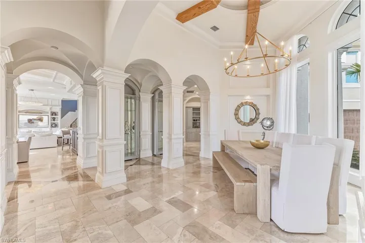 Dining room with a decorative wall, ornate columns, a high ceiling, healthy amount of natural light, and wainscoting