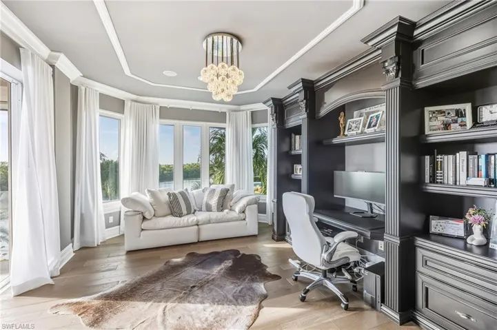 Office space featuring light wood finished floors, built in desk, a chandelier, and crown molding