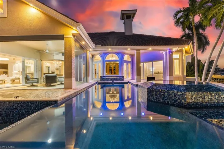 Pool at dusk featuring an outdoor pool, a patio, and a jacuzzi